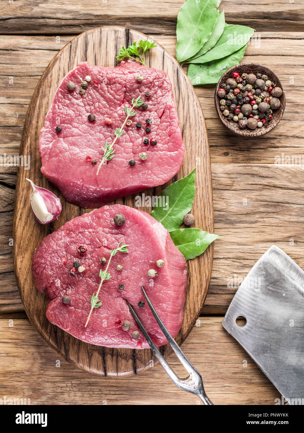 Raw beaf Steaks mit Gewürze auf einem Holzbrett. Stockfoto