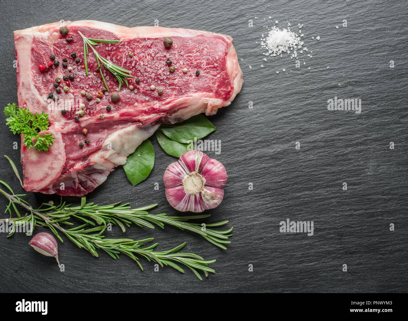 Rohes Rindfleisch Steaks mit Gewürzen auf dem schwarzen Schneidebrett. Stockfoto