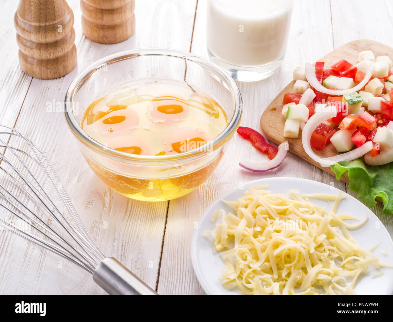 Omelett-Zutaten: Eiern, frisch geschnittene Gemüse, Milch und Käse auf dem Holztisch. Stockfoto