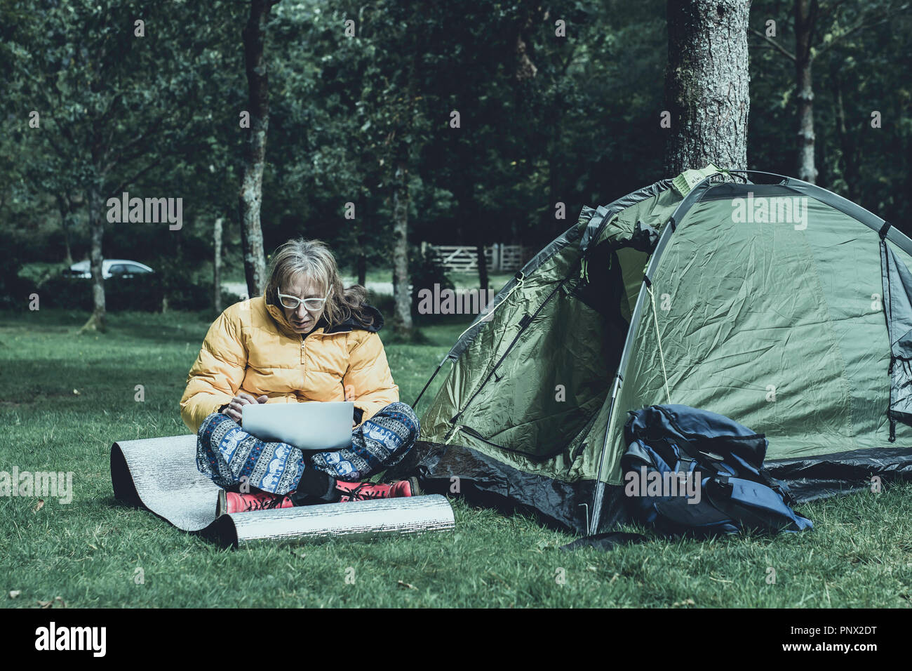 Beiläufig Mann bei der Arbeit auf seinem Laptop gekleidet, am Campingplatz in ländlichen uk. Mobile Internet Zugang, der Menschen in entlegenen Ort zu arbeiten. Stockfoto