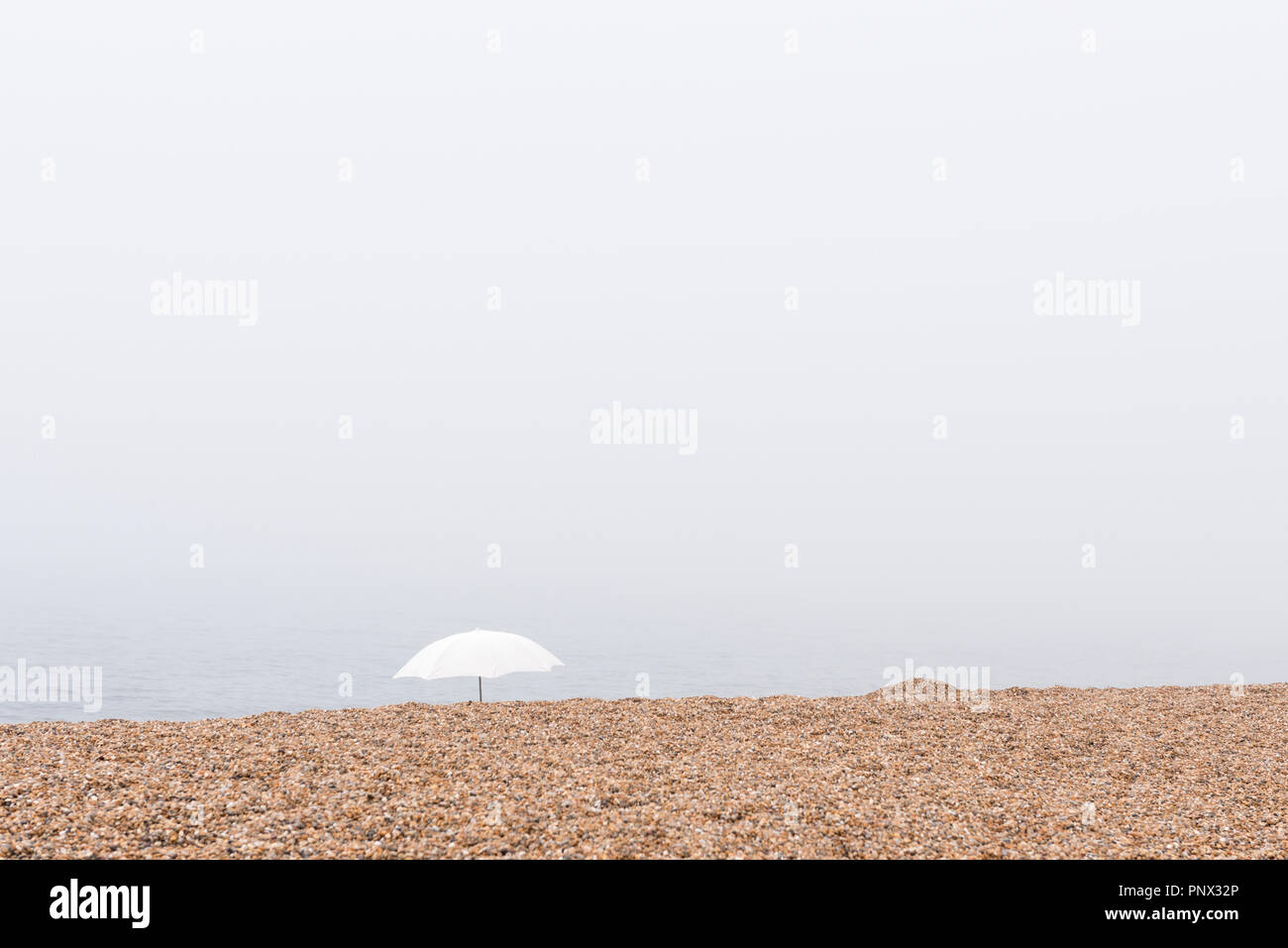 Weißer Sonnenschirm am nebligen Tag Stockfoto