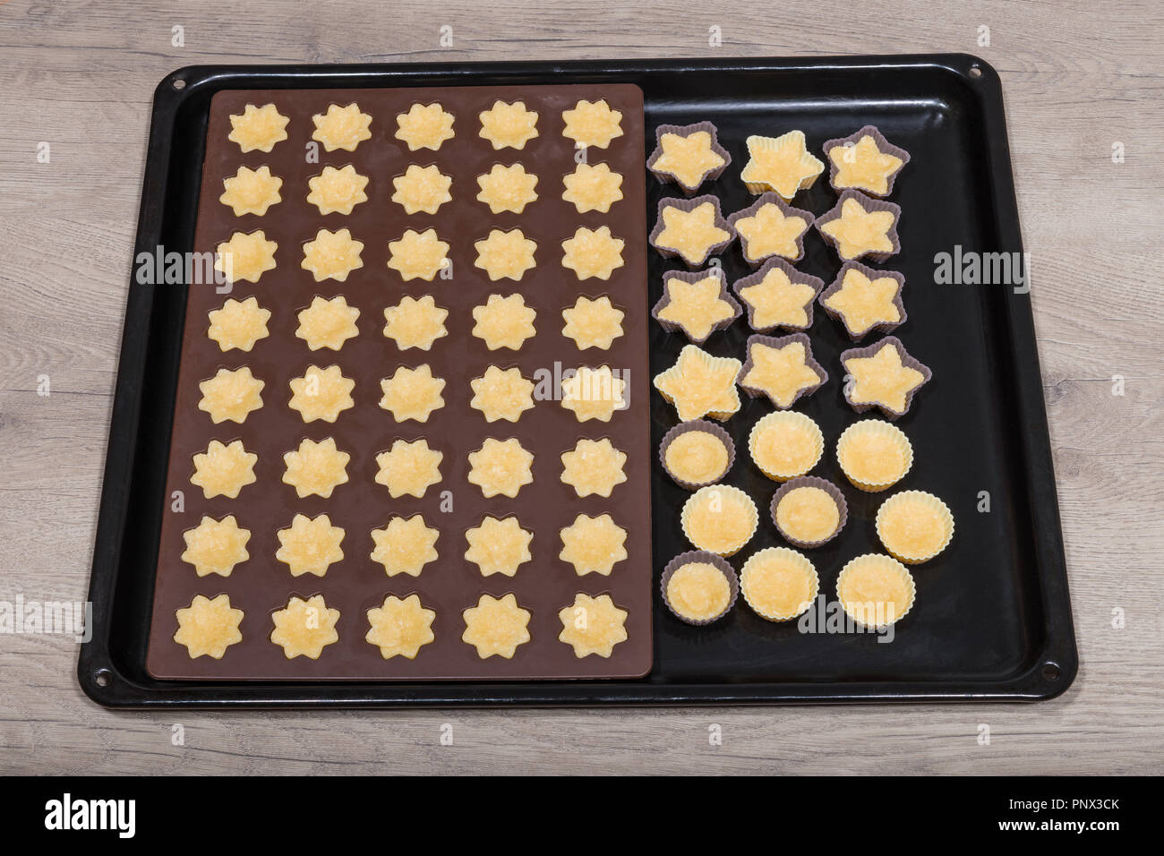 Coconut cupcakes in Silikon Formen close-up. Backformen von süßem Teig in Blume, Stern und Kreis Form gefüllt. Weihnachten und Neujahr Cookies. Stockfoto