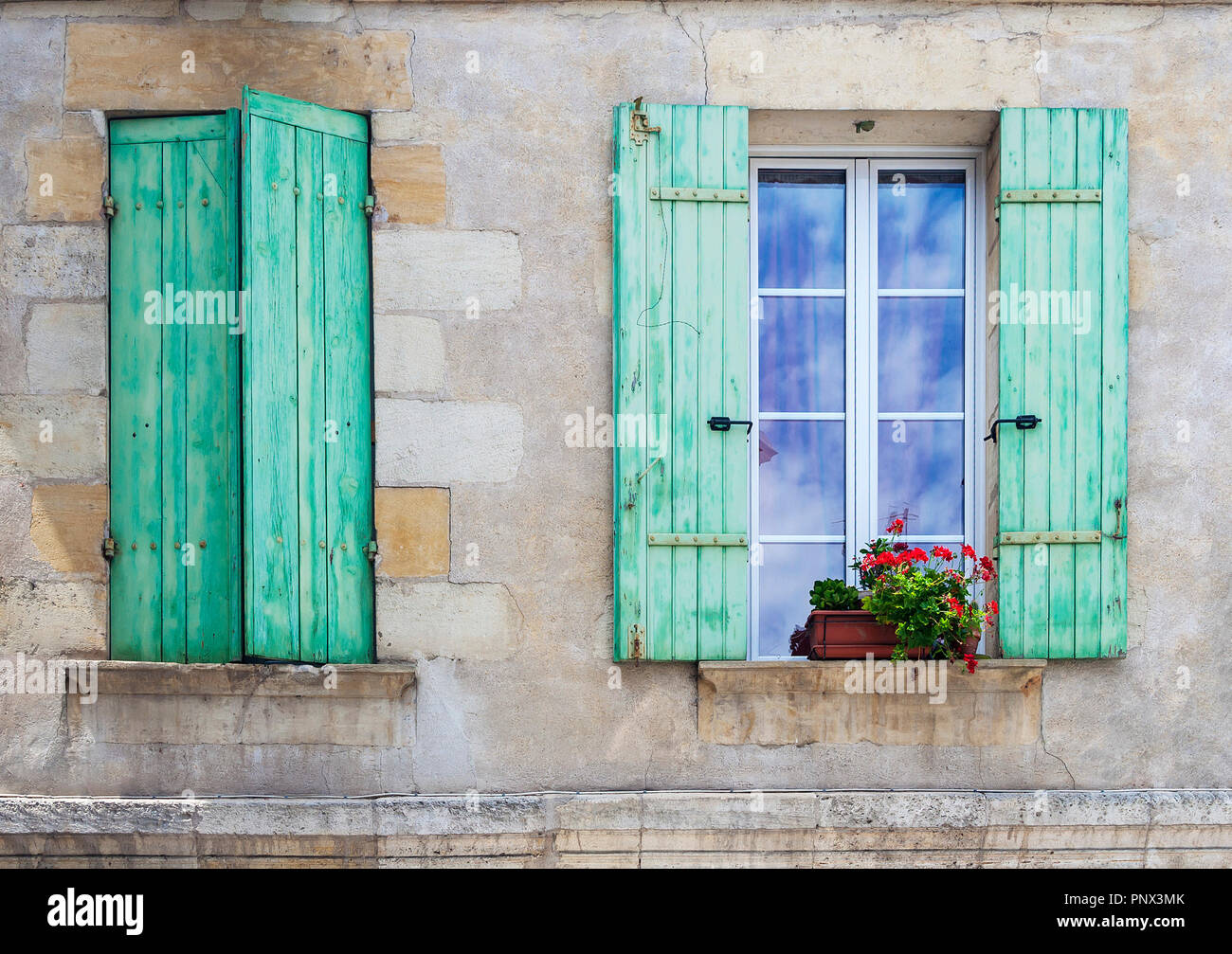 Rustikale französische Fensterläden mit auf offenen und eine mit Pflanzen auf der Fensterbank geschlossen Stockfoto