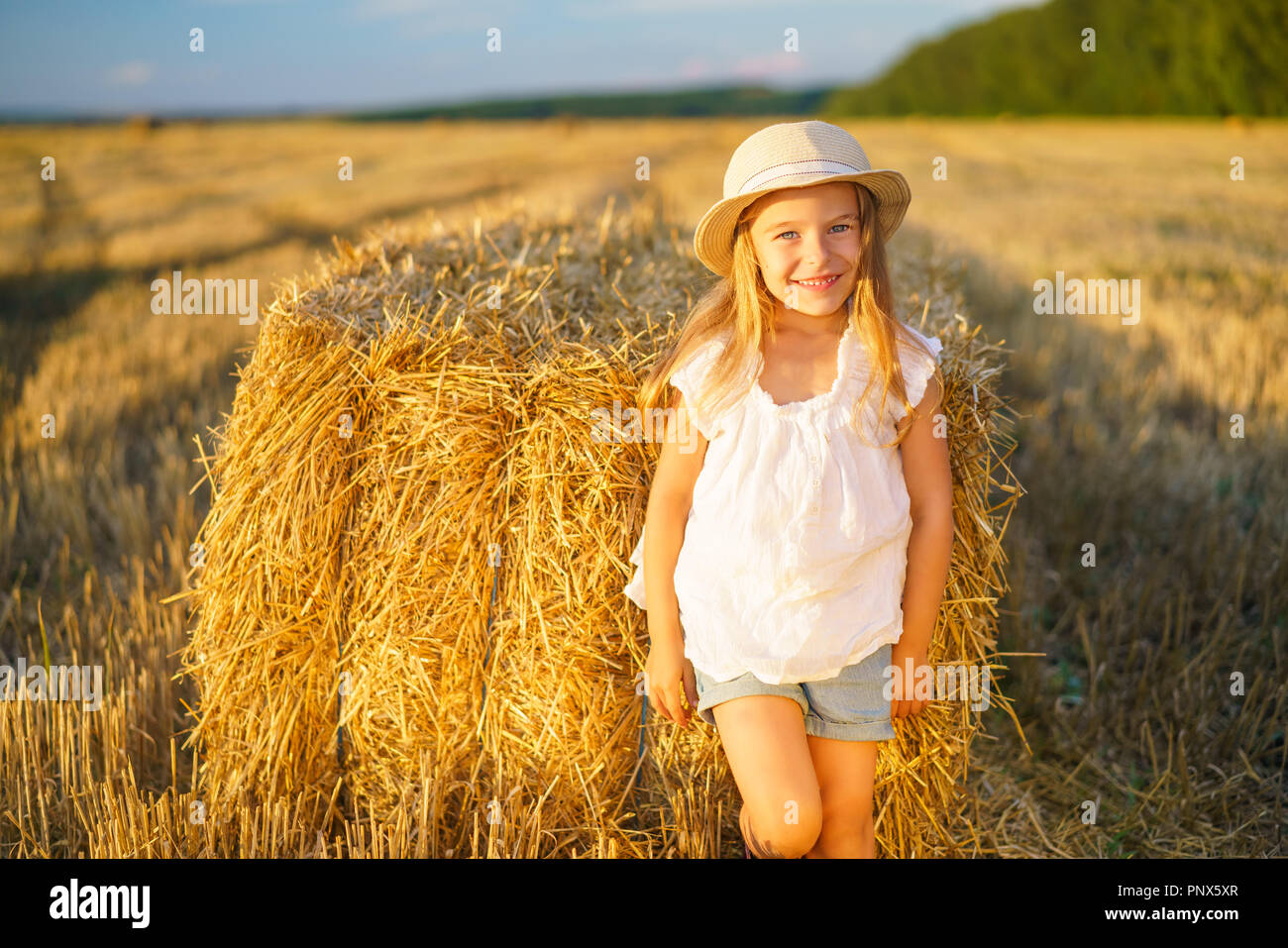 Kleines Mädchen in einem Feld mit Heu Rollen Stockfoto