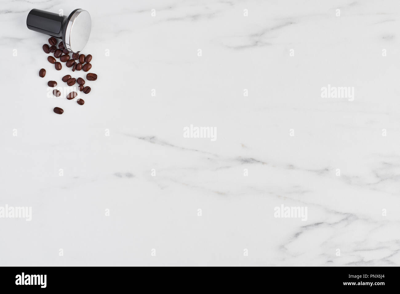 Blick von oben auf die schwarzen Kaffee Stampfer und gerösteten Kaffeebohnen auf weißem Hintergrund. Flach mit kopieren. Stockfoto
