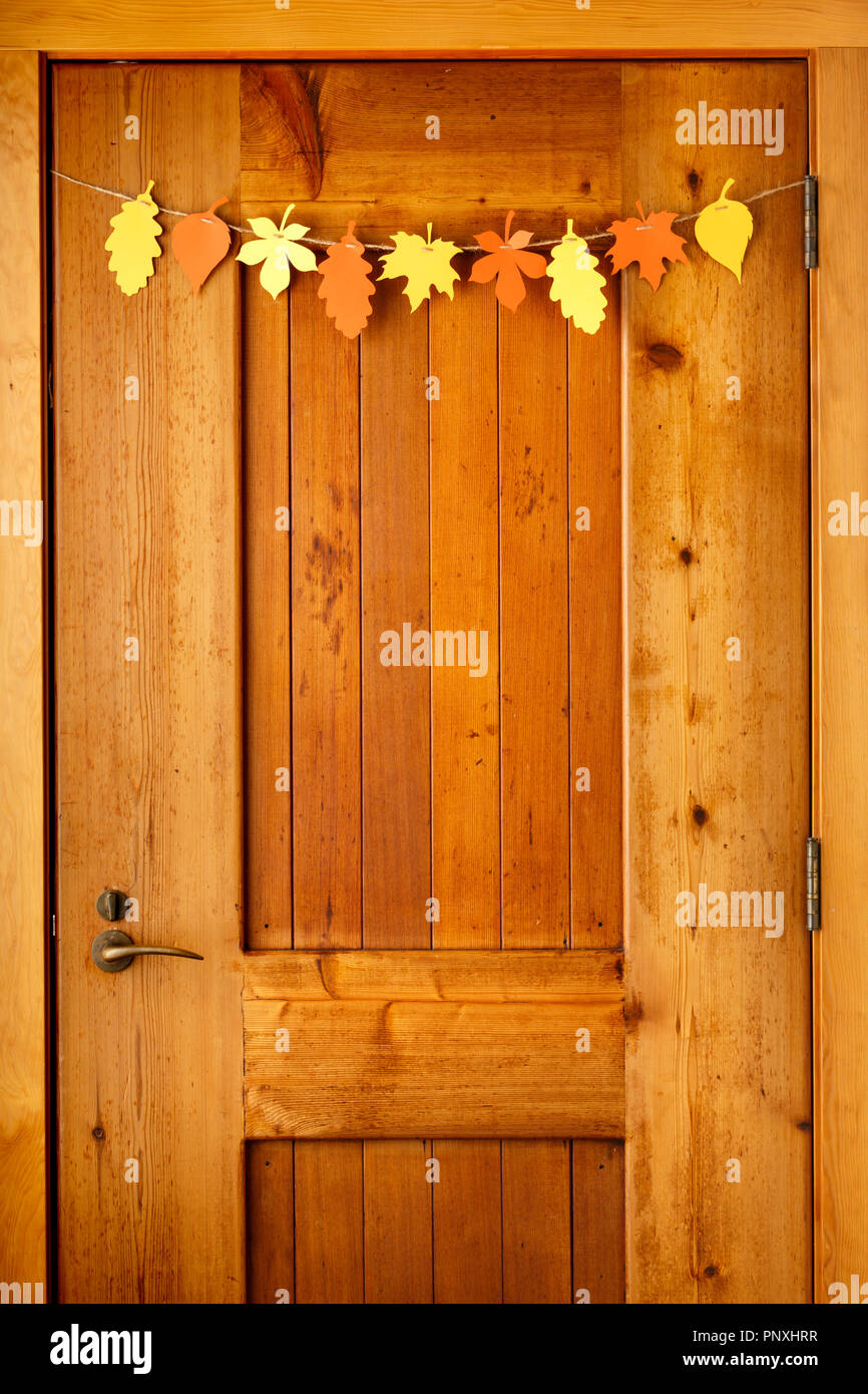 Einfachen, rustikalen Landhausstil Thanksgiving home Dekorationen Papier Handwerk Girlande banner Buntes Herbstlaub auf hölzernen Tür Hintergrund Stockfoto