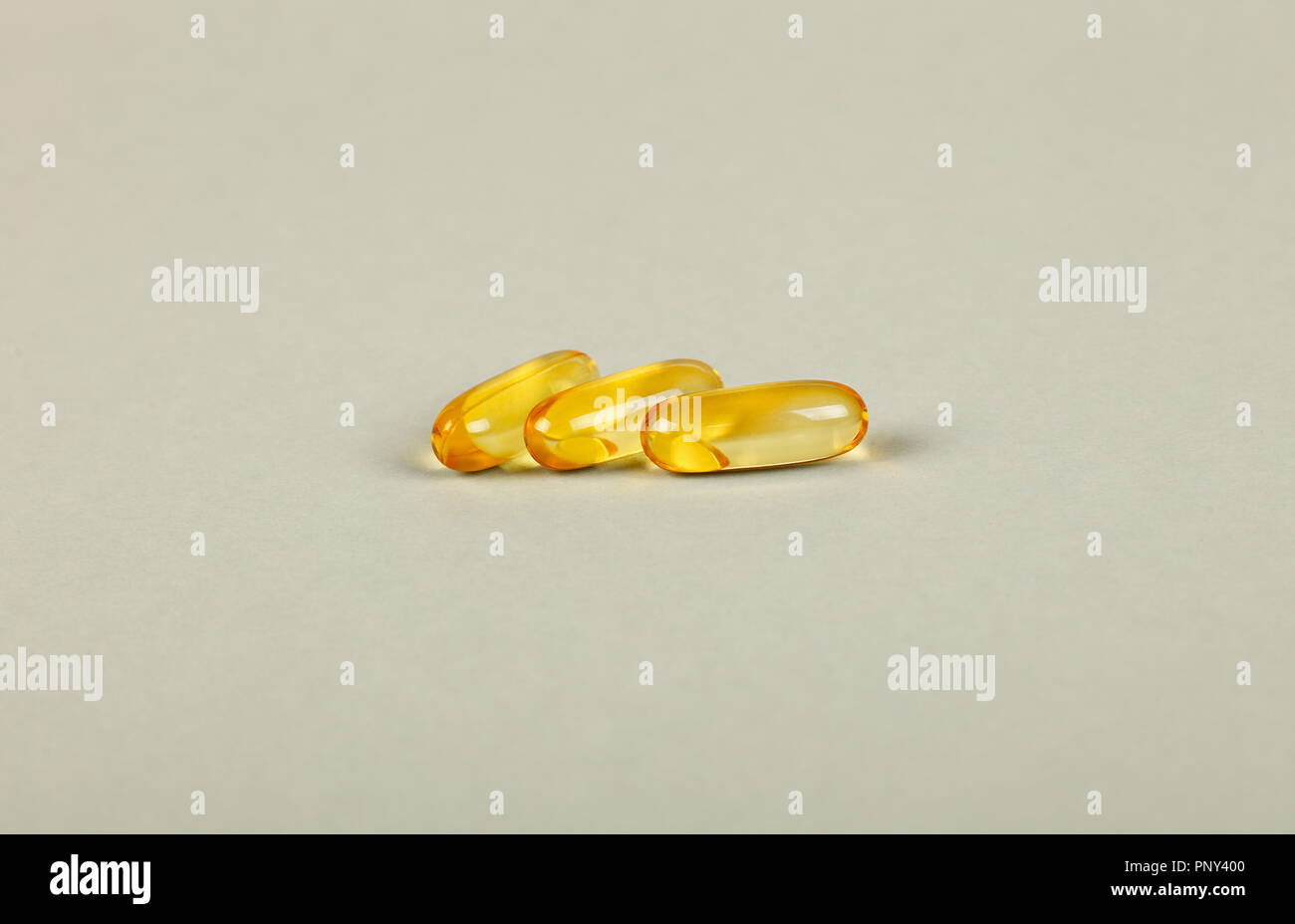 Schließen Sie bis zu drei gelbe Vitaminen und essentiellen Omega 3 Fischöl gel cap Pillen über grauer Hintergrund mit Kopie Raum, Hohe Betrachtungswinkel Stockfoto