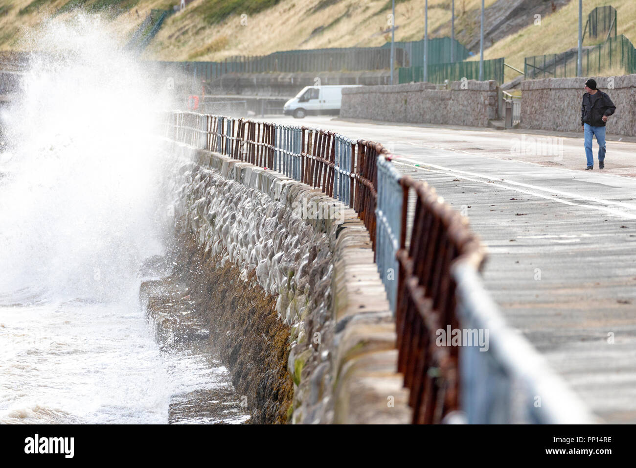 Colwyn Bay, Großbritannien September 2018 UK Wetter: Ein herbstliches Gefühl in der Luft auf die Herbst-tagundnachtgleiche am ersten Tag des Herbstes mit kühleren Temperaturen und windigen Bedingungen an der Küste Stadt Colwyn Bay, North Wales. Eine Person zu Fuß Weg zurück vom Meer Wand wie Wellen in es in Colwyn Bay, North Wales Stockfoto