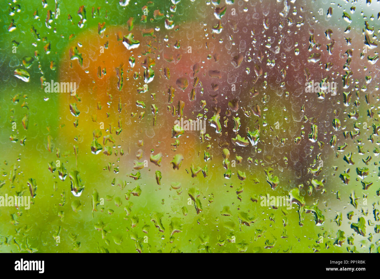 Blick auf einen außen Schwingen durch ein Fenster mit Regentropfen an einem Sommertag abgedeckt. Stockfoto