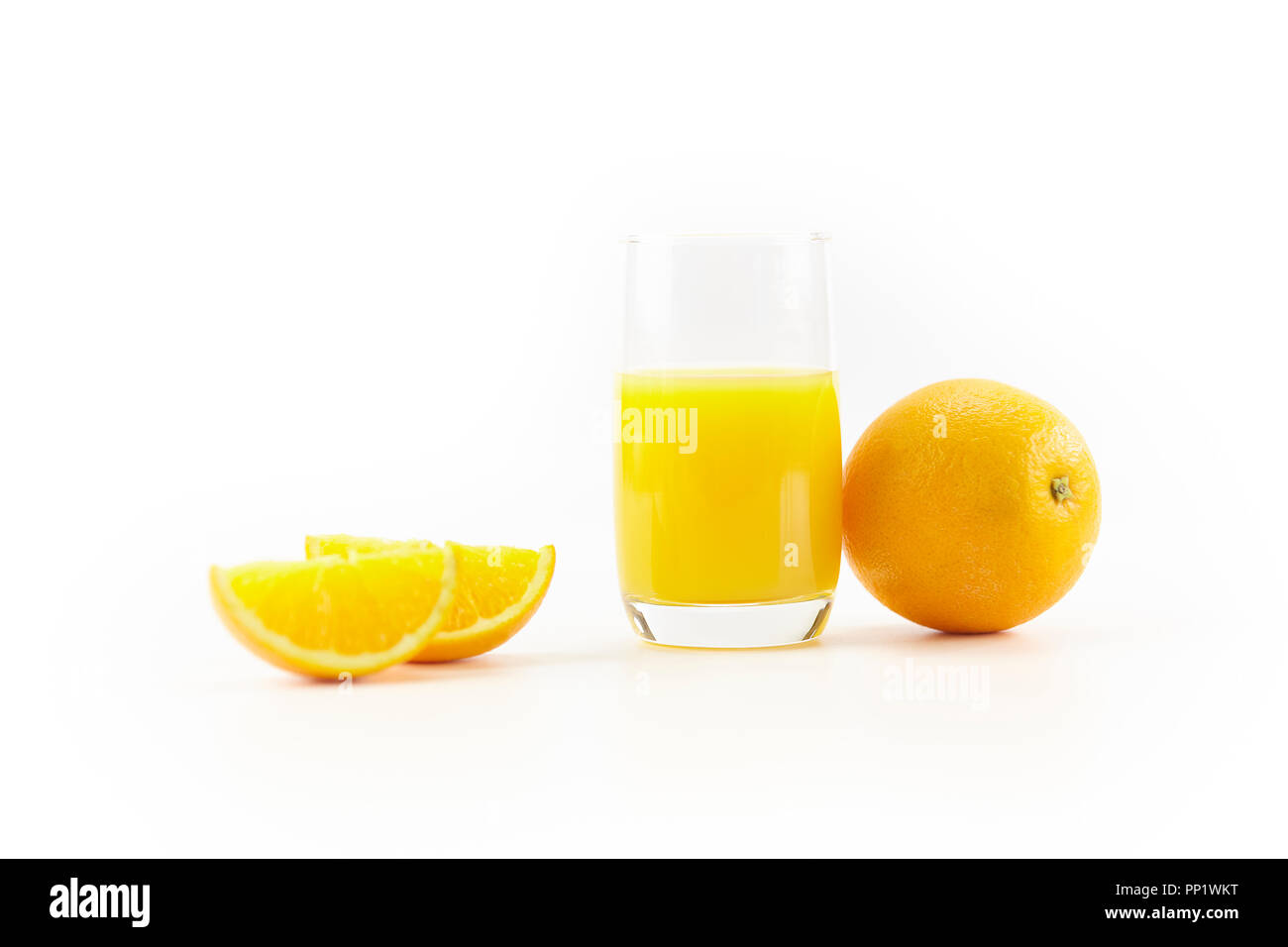 Orangen und ein Glas Orangensaft auf weißem Hintergrund. Stockfoto