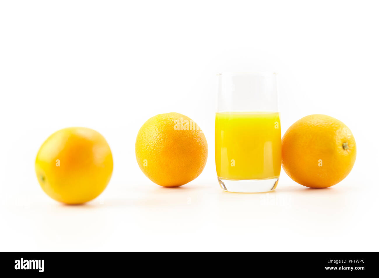 Drei Orangen und ein Glas Orangensaft auf weißem Hintergrund. Stockfoto