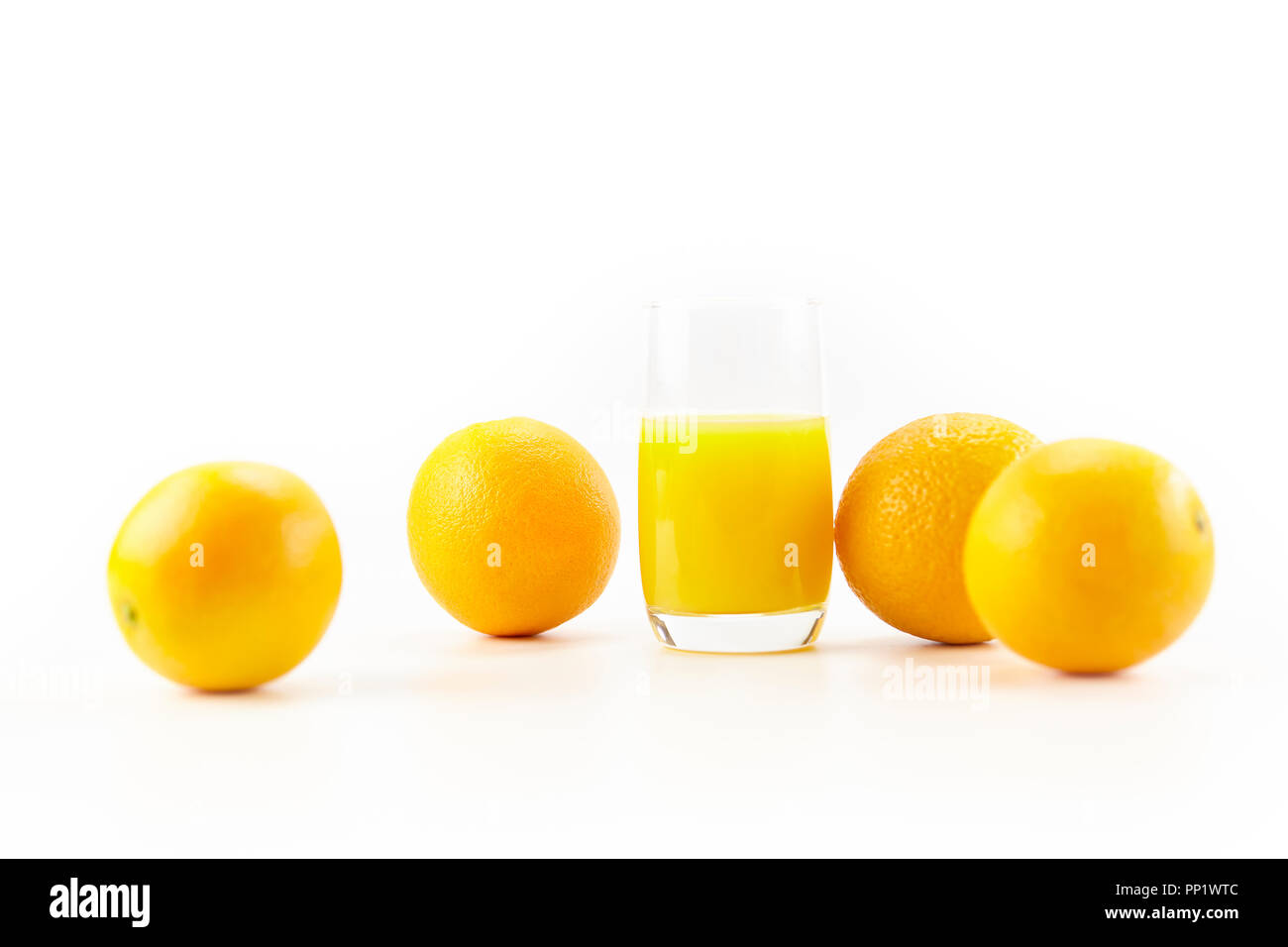 Vier Orangen und ein Glas Orangensaft auf weißem Hintergrund. Stockfoto