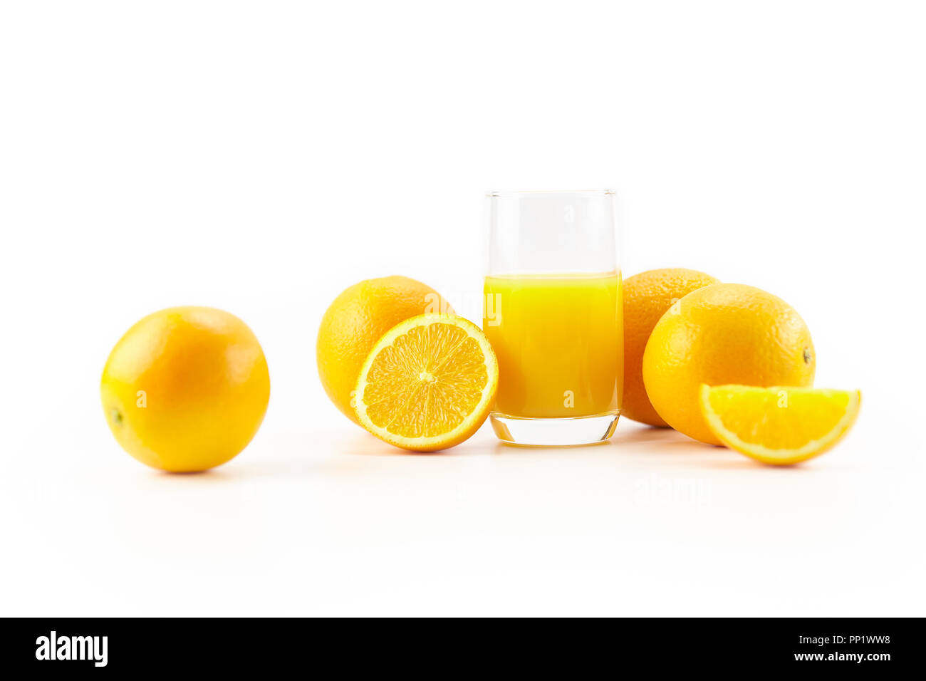 Orangen und ein Glas Orangensaft auf weißem Hintergrund. Stockfoto