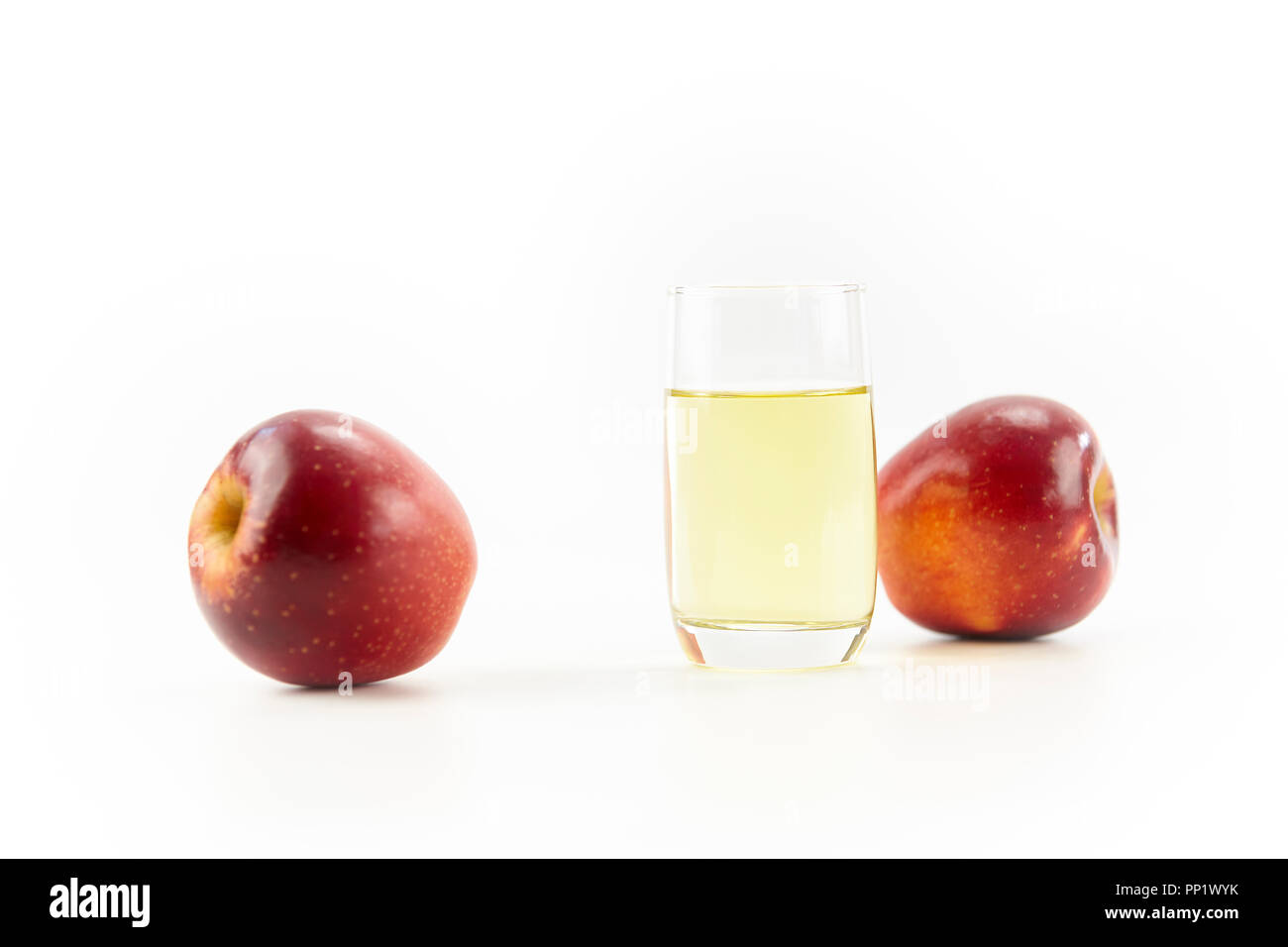 Zwei Äpfel und ein Glas Apfelsaft auf weißem Hintergrund. Stockfoto