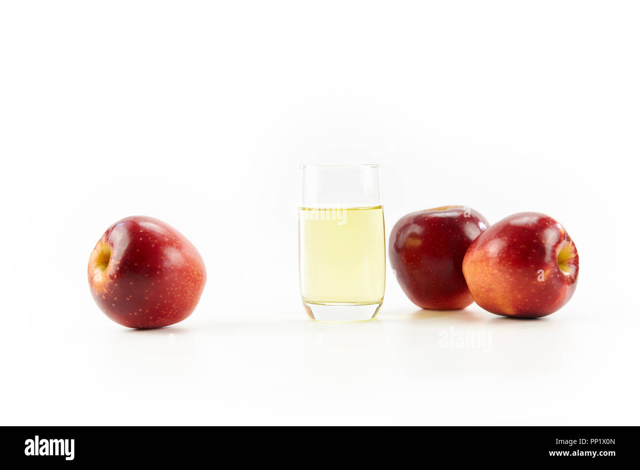 Drei Äpfel und ein Glas Apfelsaft auf weißem Hintergrund. Stockfoto