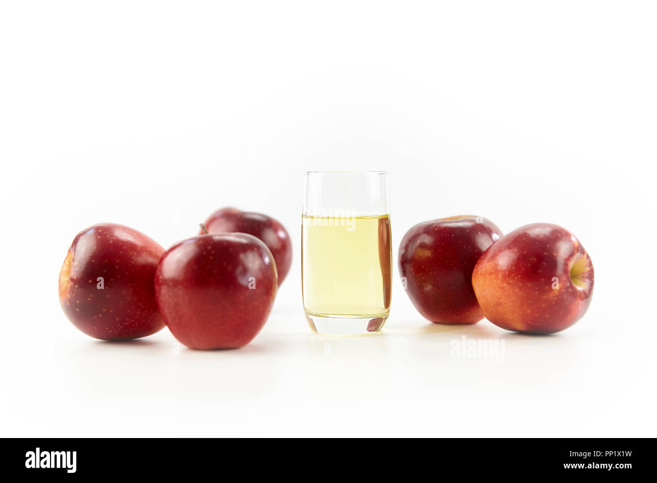 Fünf Äpfel und ein Glas Apfelsaft auf weißem Hintergrund. Stockfoto