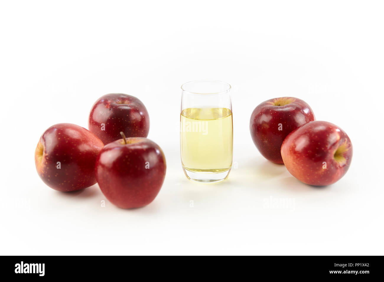 Fünf Äpfel und ein Glas Apfelsaft auf weißem Hintergrund. Stockfoto