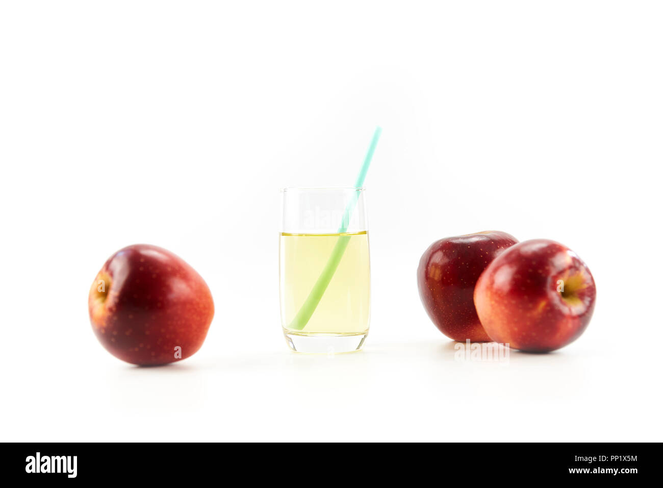 Drei Äpfel und ein Glas Apfelsaft auf weißem Hintergrund. Stockfoto