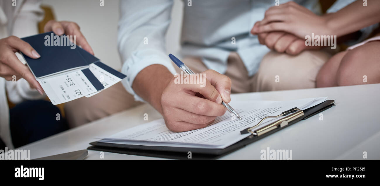 Junge paar schöne sitzend mit Manager im Reisebüro Büro- und unterzeichnen Vertrag für einen Urlaub. Close-up Konzept für Reisebüro Stockfoto