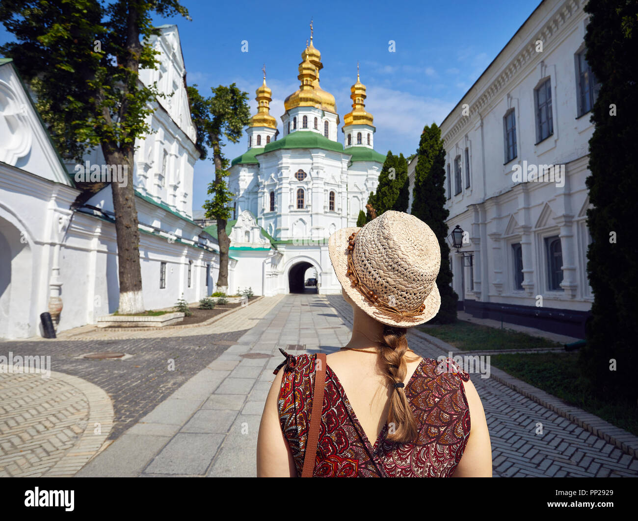 Frau mit Hut in die Kirche mit goldenen Kuppeln in Kiew Pechersk Lavra Christian komplex. Alte historische Architektur in Kiew, Ukraine Stockfoto