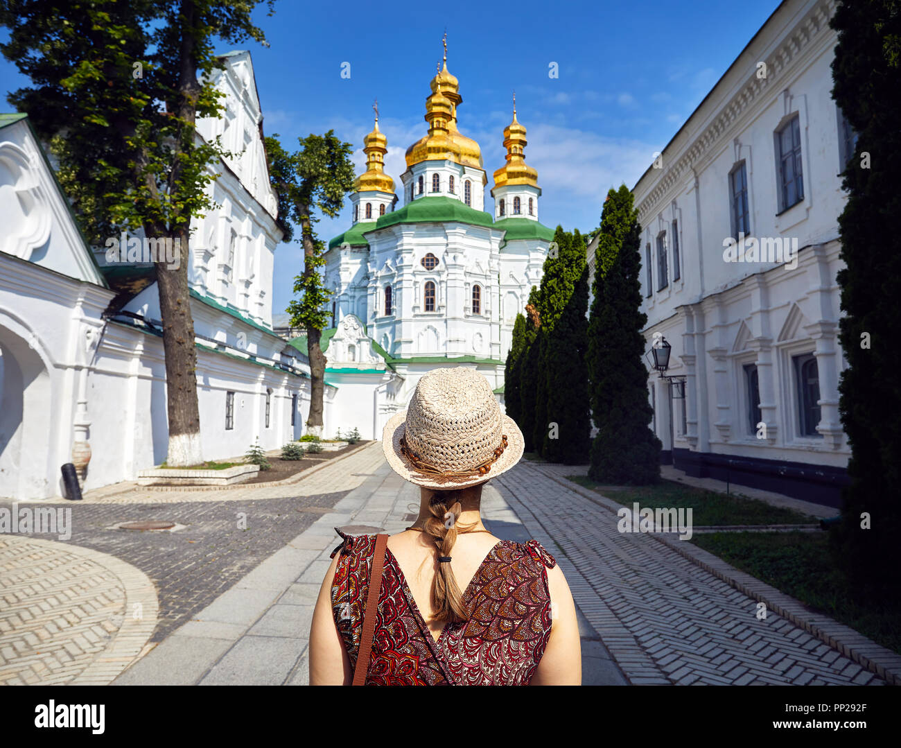 Frau mit Hut in die Kirche mit goldenen Kuppeln in Kiew Pechersk Lavra Christian komplex. Alte historische Architektur in Kiew, Ukraine Stockfoto