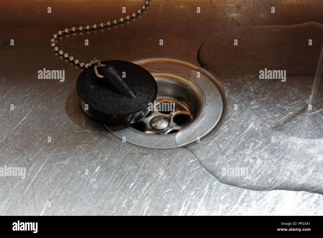 Gummistopfen mit Bohrung in Edelstahl Waschbecken mit Wasser Ablassen des Öls Stockfoto