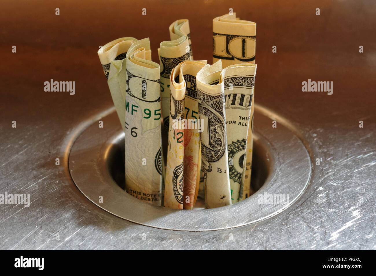 Werfen Geld in den Sand gesetzt - Amerikanische Dollar in einem Abfluss aus Edelstahl. Stockfoto
