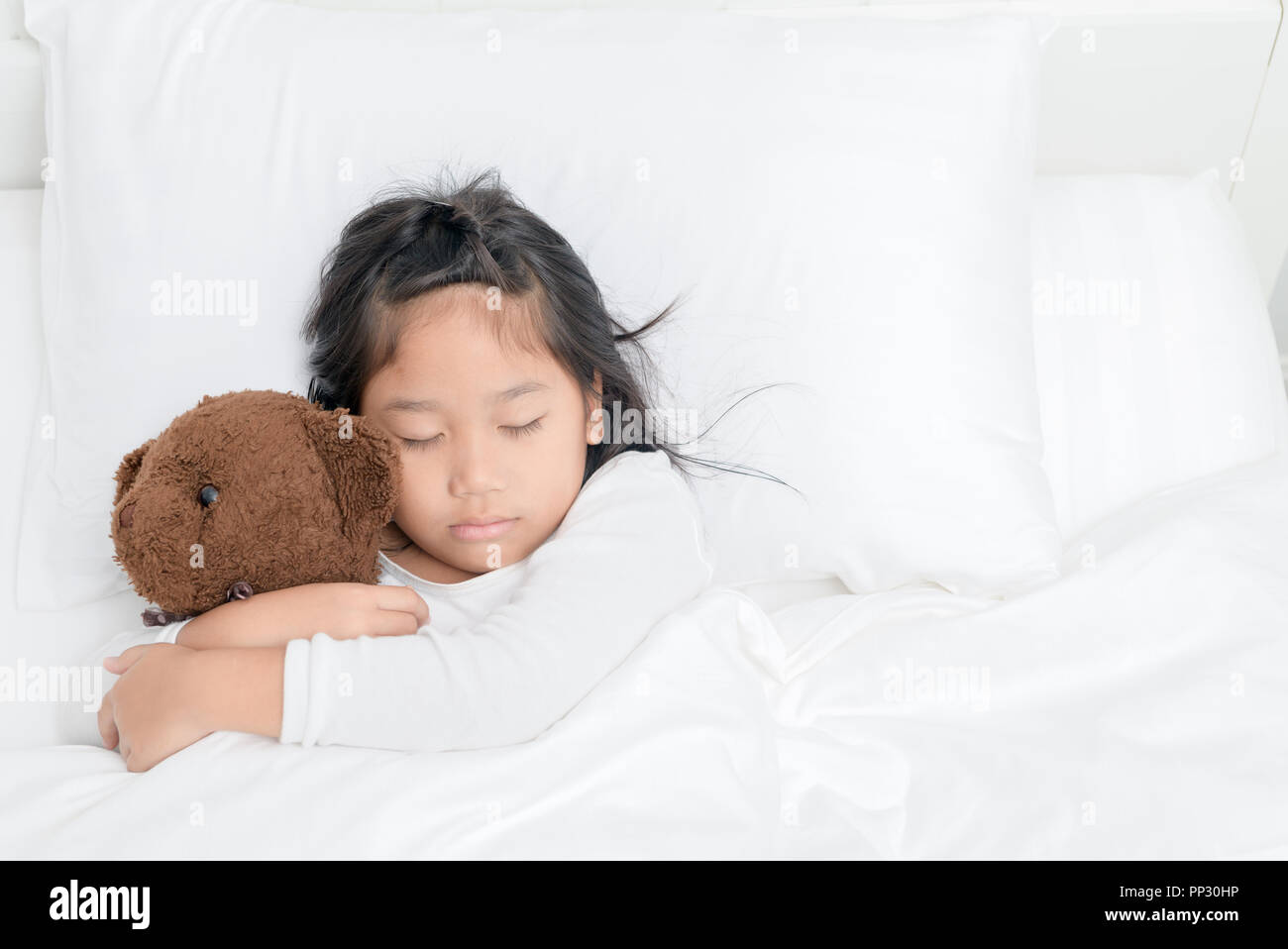 Hübsches kleines Mädchen ist das Umarmen Teddybär beim Schlafen im Bett zu Hause, Ansicht von oben ruht für gesundes Konzept Stockfoto