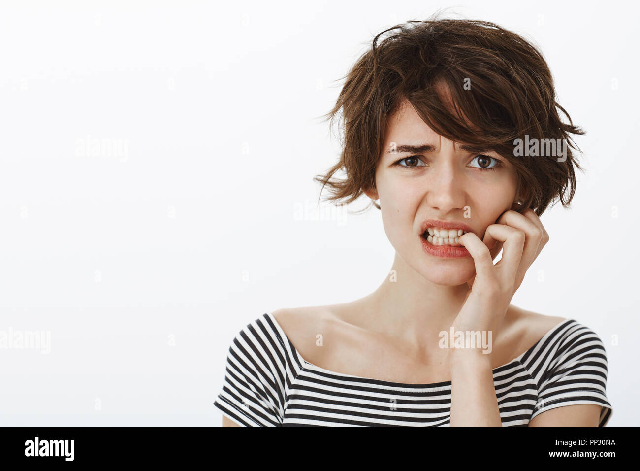 Mädchen suggesring aus Angst und übertrieben. Portrait von besorgt intensive Freundin mit kurzen unordentlichen Haar, runzelte die Stirn und beißen Fingernägel während Nervös, von Gedanken gestört Stockfoto