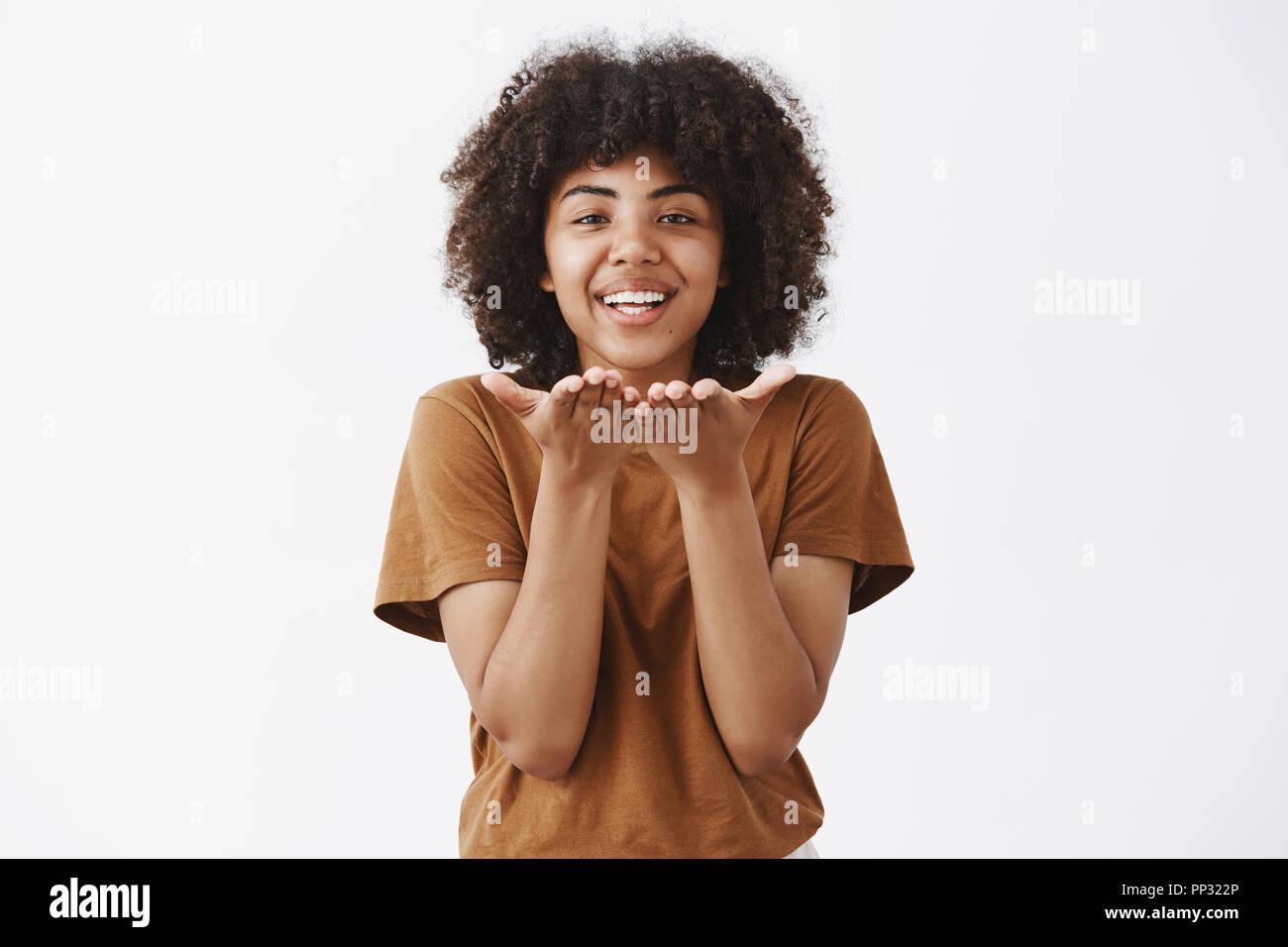 Taille-up Shot sorglosen zart und romantisch afrikanische amerikanische Freundin Ausdruck der Zuneigung und Liebe, während Sie Wind Kiss oder mwah freudig und lächelnd Palmen in der Nähe von Mund über graue Wand Stockfoto