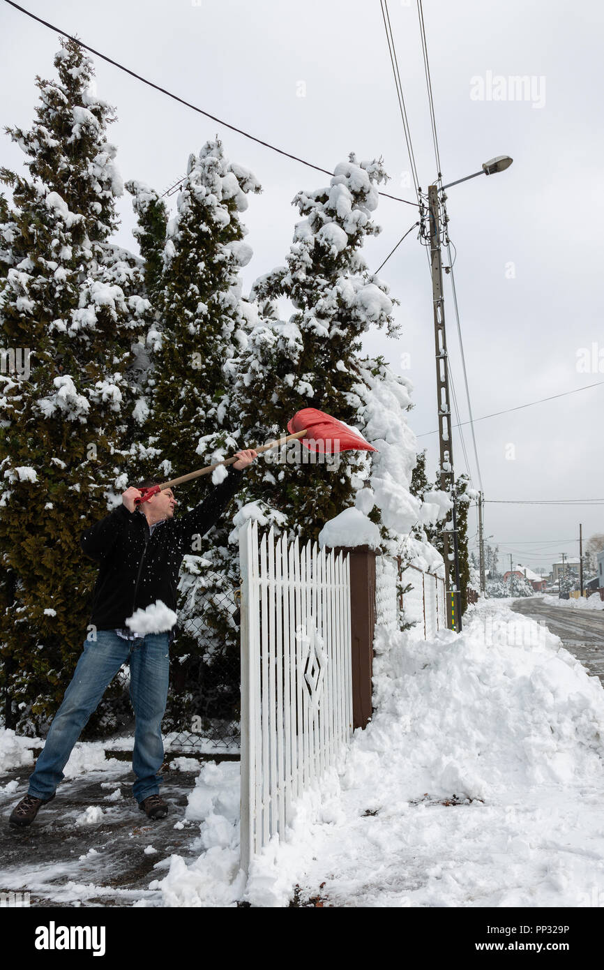 Mann mit roten Schneeschaufel reinigt bis Schnee. Stockfoto