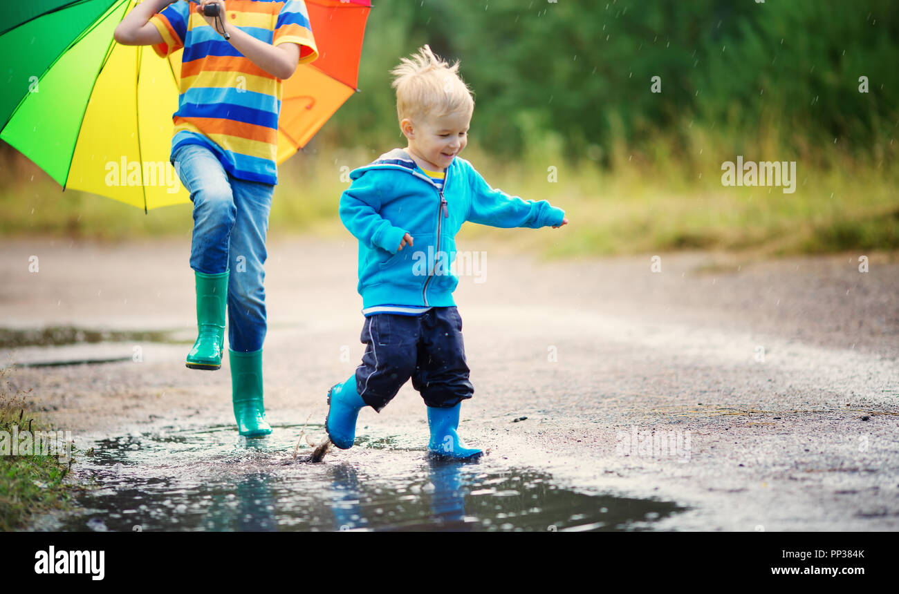 Kinder Wandern in Gummistiefel in Pfütze auf Regenwetter Stockfoto