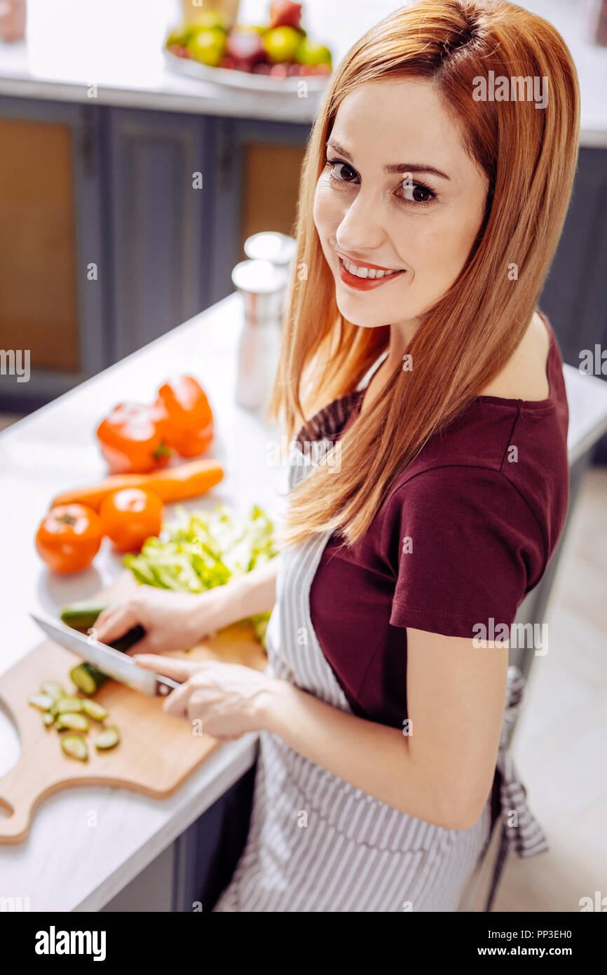 Schöne Frau mit Messer in ihrer linken Hand und Schneiden Gurken Stockfoto