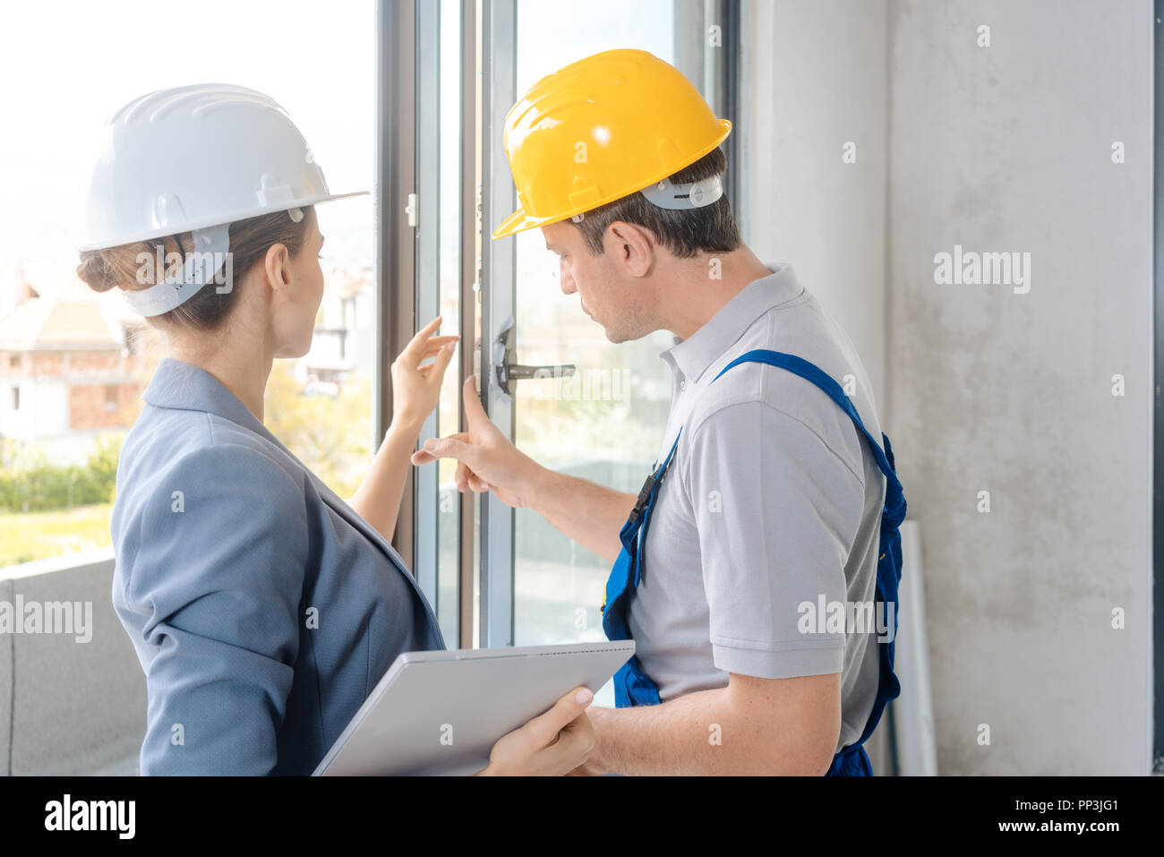 Architekt und Bauarbeiter prüfen Windows vor Ort Stockfoto