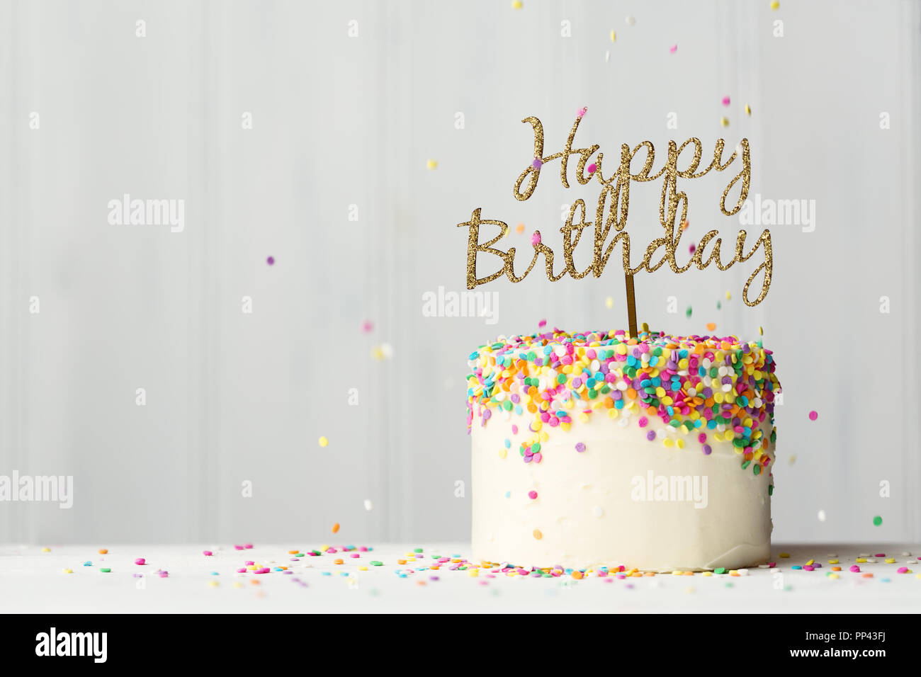 Bunter Geburtstagskuchen mit goldenen happy birthday Banner und fallende besprüht Stockfoto