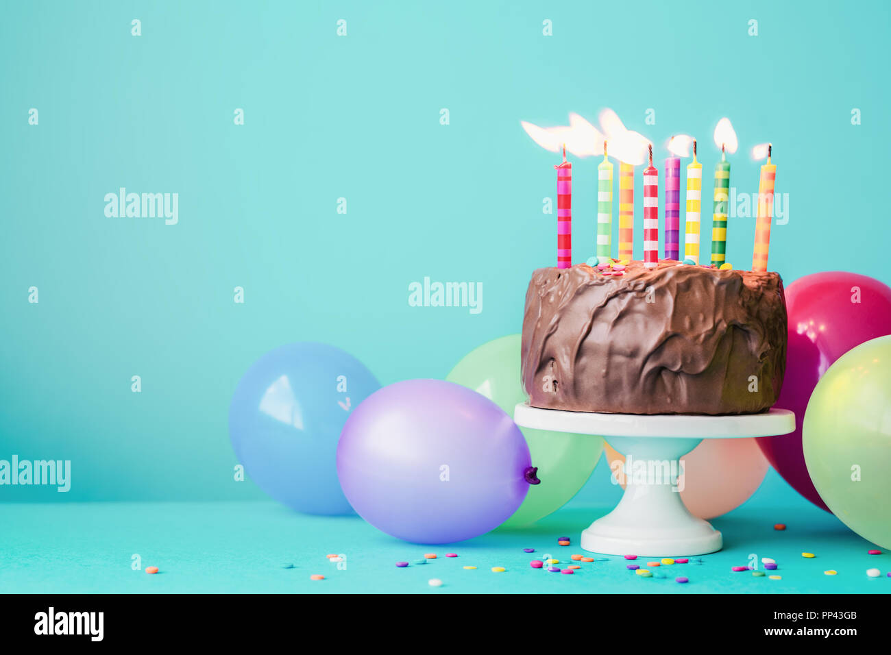 Schokolade Kuchen mit bunten Kerzen und Ballons Stockfoto