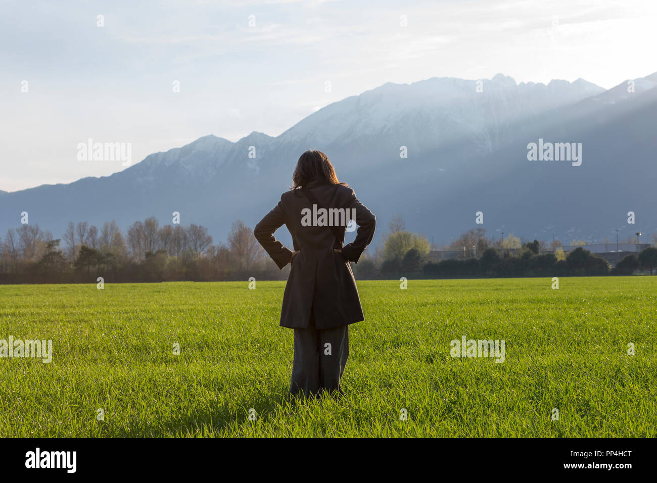 Frau, die auf einem grünen Feld mit schneebedeckten Berg in der Schweiz. Stockfoto