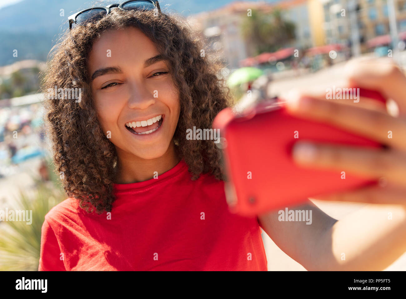 Schöne happy gemischten Rasse Afrikanische Amerikanische junge frau mädchen Teenager weibliches Kind lächelnd mit perfekte Zähne unter selfie Foto mit roten Zelle p Stockfoto