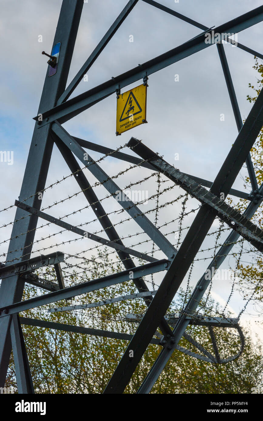 Nahaufnahme eines diagonal auf einem Bein der Stahlkonstruktion eines Britischen hohe Spannung Strom Pylon mit gelben Warnschild, Lancashire, England, Großbritannien Stockfoto
