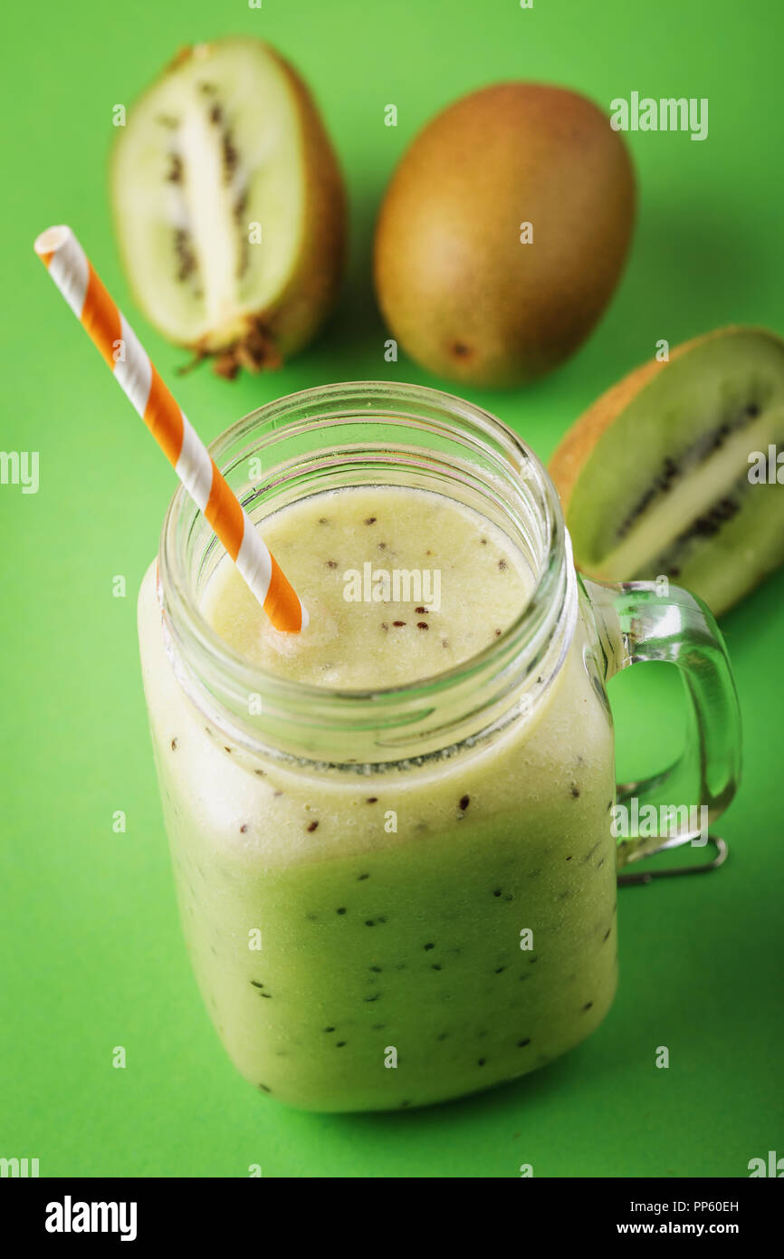 Smoothies aus reifen Kiwi in einem durchsichtigen Glas gekocht mit Obst auf einem grünen Hintergrund Stockfoto
