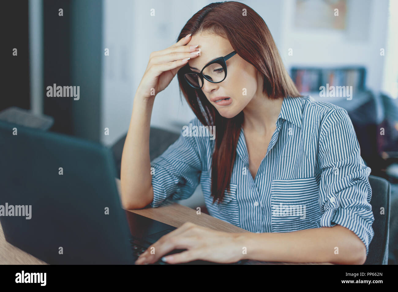 Junge rothaarige Frau am Laptop auf der Suche zu Hause unangenehm überrascht, per e-mail Benachrichtigung lesen schlechte Nachrichten online abo Schockiert Stockfoto