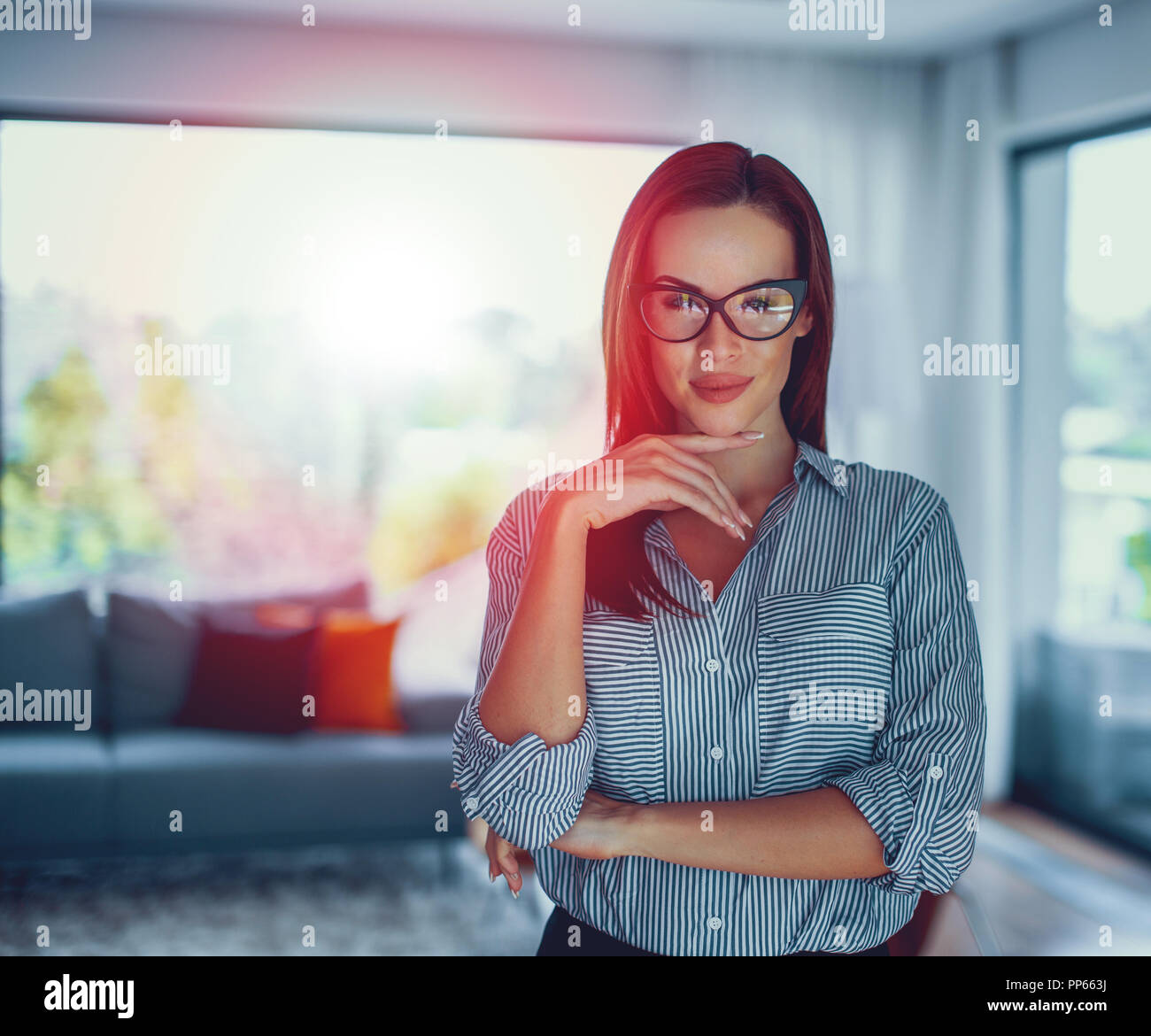 Junge zuversichtlich Moderne nerd Frau im Wohnzimmer zuhause im Sonnenuntergang posing Stockfoto