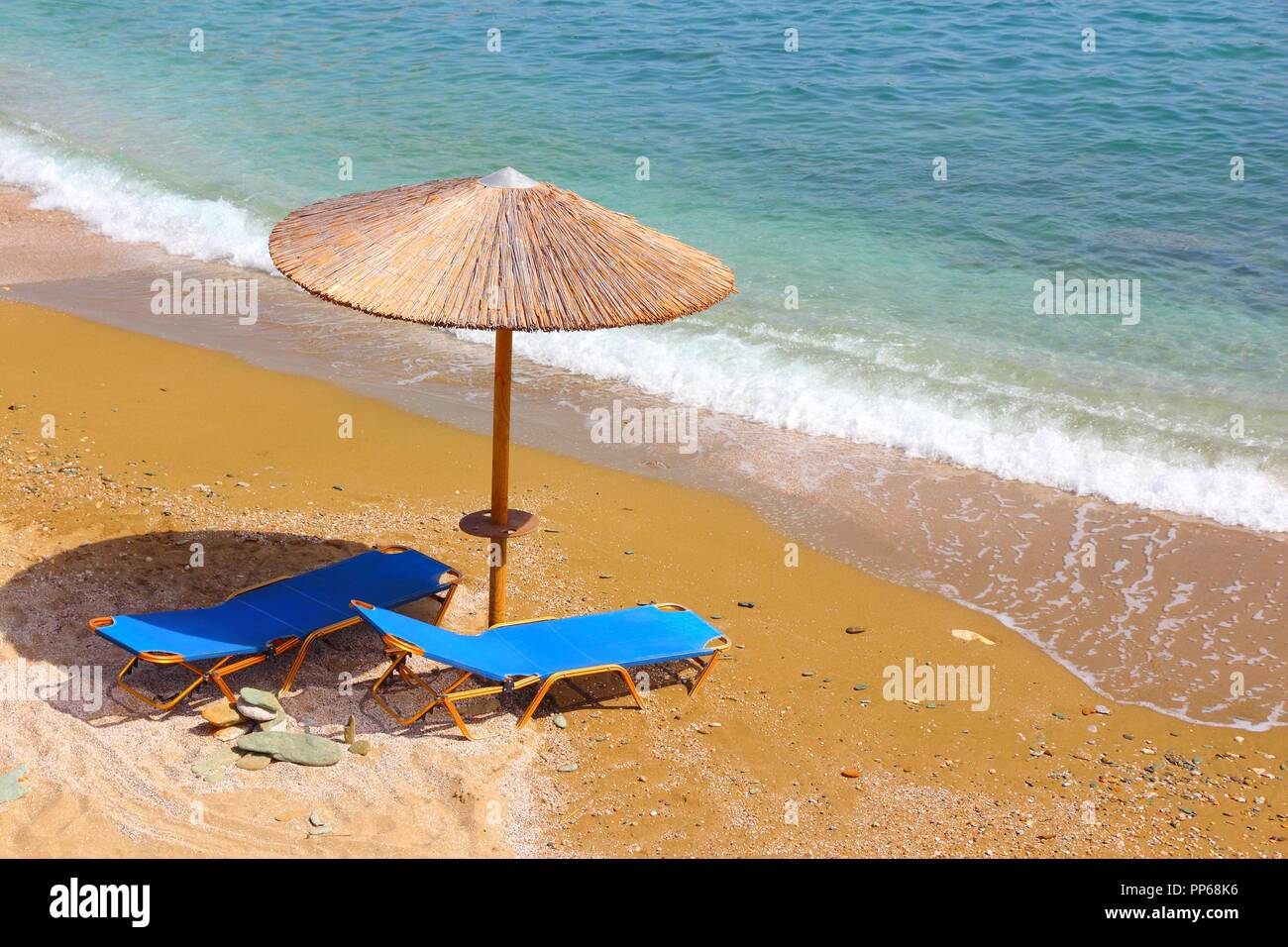 Griechenland - Insel Kreta. Sonnenliegen und ein Sonnenschirm am Strand von Agia Pelagia. Stockfoto