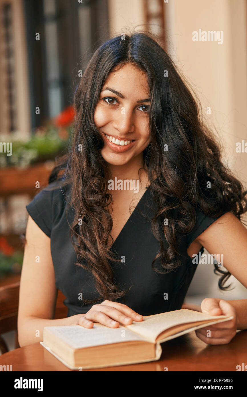 Junge arabische Frau mit einem Buch in einem Cafe Stockfoto