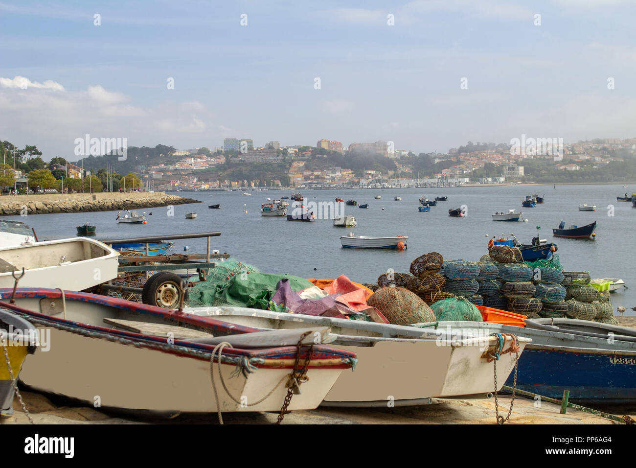 Porto, Portugal. Kleine Boote und Angelausrüstung am Kai und kleine Boote in der Bucht mit der Stadt Porto, Portugal im Hintergrund. Stockfoto