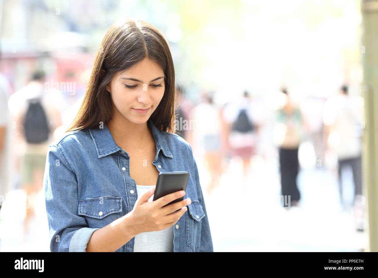 Schöne entspannte jugendlich mit einem Smart Phone zu Fuß auf der Straße Stockfoto