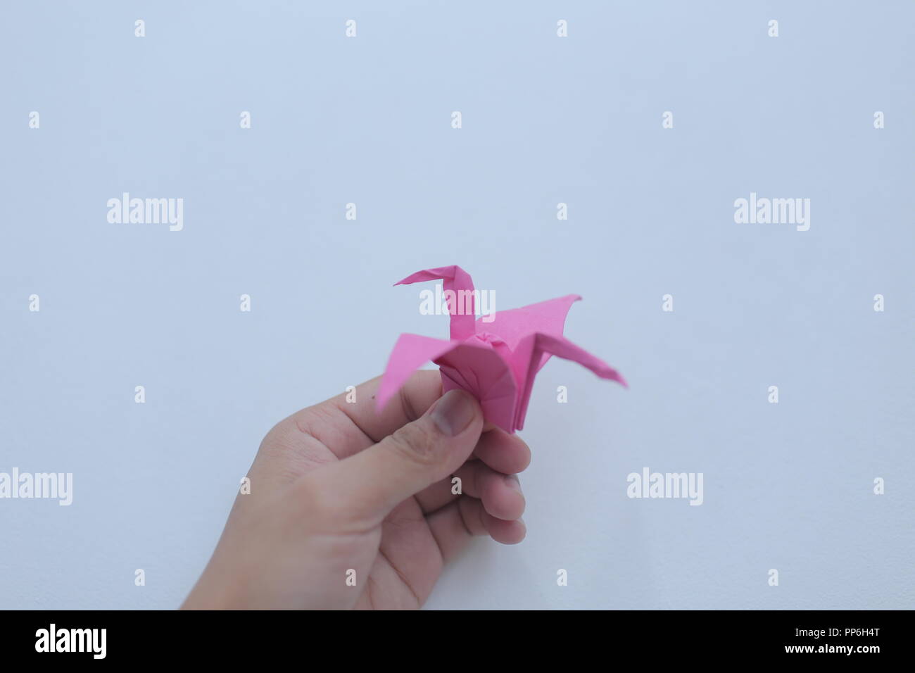 Hand mit rosa origami Papier mit Vogel Form mit isolierten weißen Hintergrund. Stockfoto