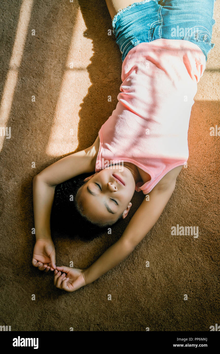 Mädchen mit auf Wohnzimmer Teppich im Sonnenlicht Stockfoto