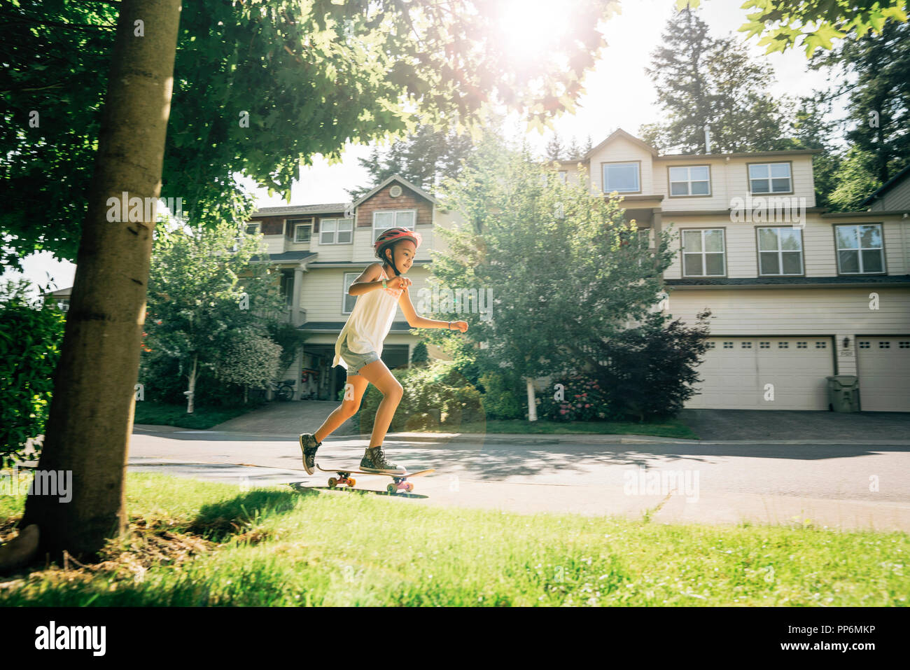 Tween Girl Schlittschuhlaufen auf Skateboard auf Bürgersteig in Wohngegend Stockfoto