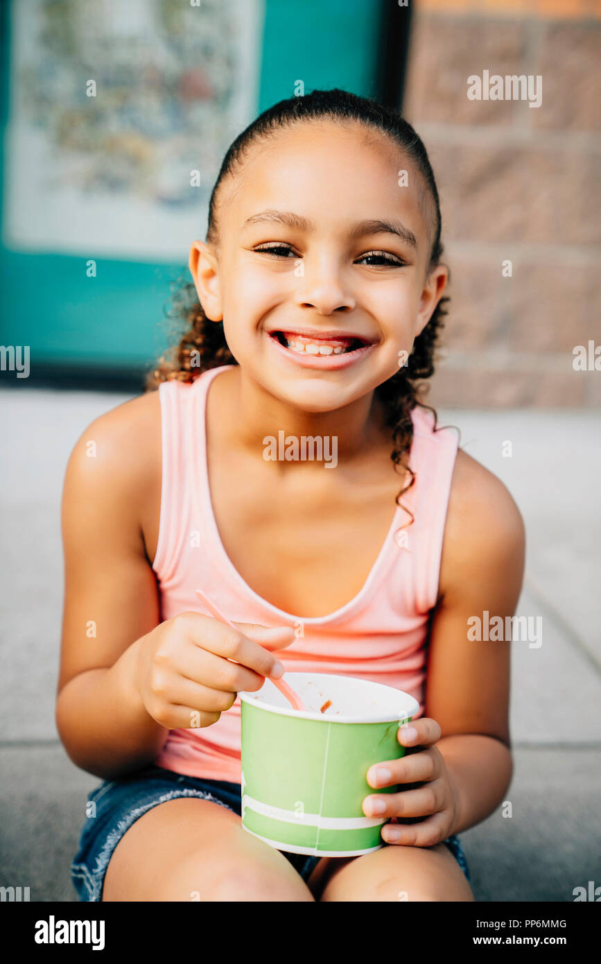 Lächelnde Mädchen sitzen auf Schritte Eis essen Stockfoto